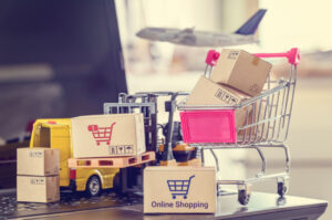 Miniature boxes, trolley and trucks on a laptop keyboard depicting ecommerce.