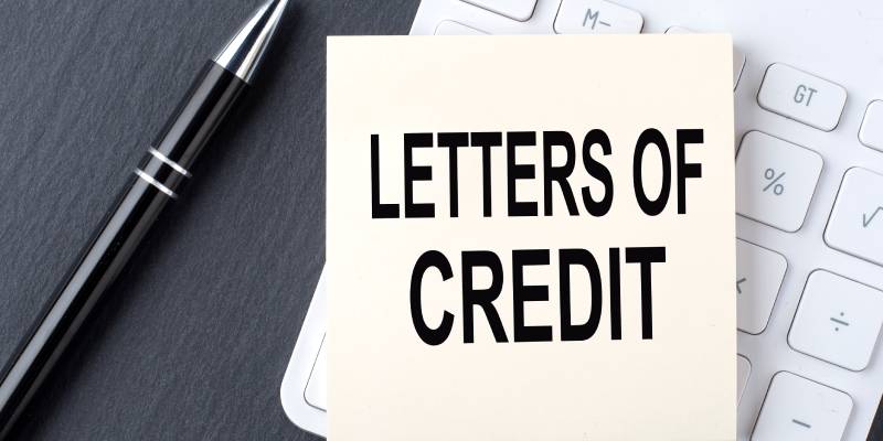 The term letters of credit is written on a white notepad with a calculator and pen kept near it.