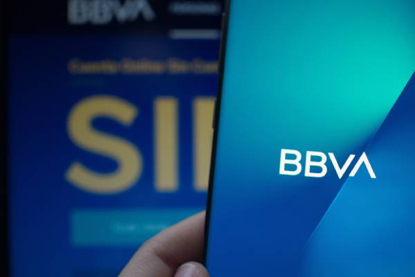 Image of BBVA app on smartphone and VISA card kept behind it.
