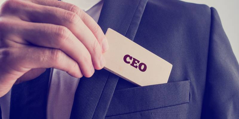 An image of a businessman showing a wooden card reading - CEO.