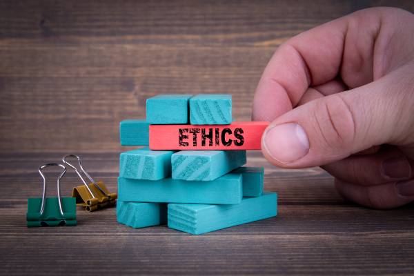 Image of a hand pulling out a wooden block with the word ethics written on it.