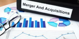 A file with name merger and acquisition kept on a table along with financial graphs,a pencil and a spectacle.