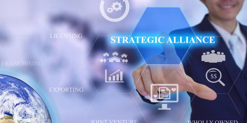 Image of a person touching the word strategic alliance and related icons shown on a virtual screen in front of him.