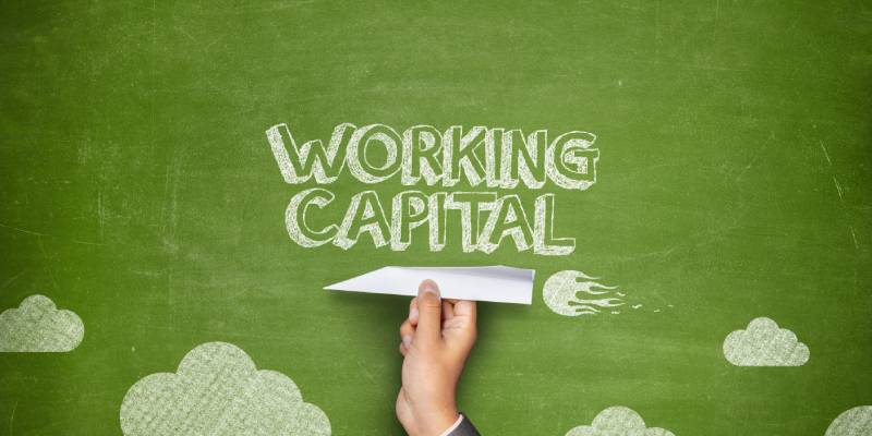The term working capital mentioned on a green board and a businessman hand holding paper plane indicating working capital funding